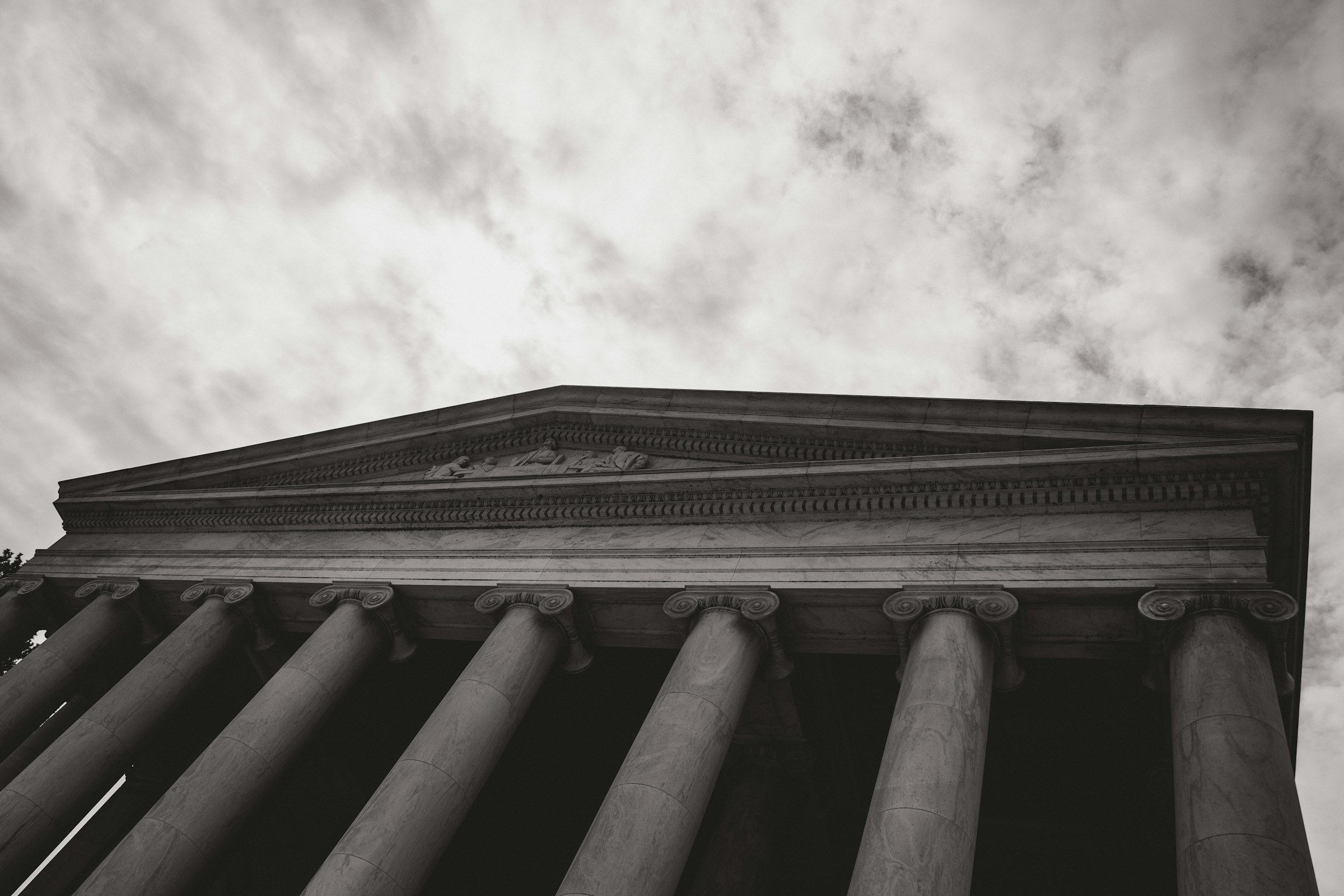 Classical columns beneath a clouded sky.